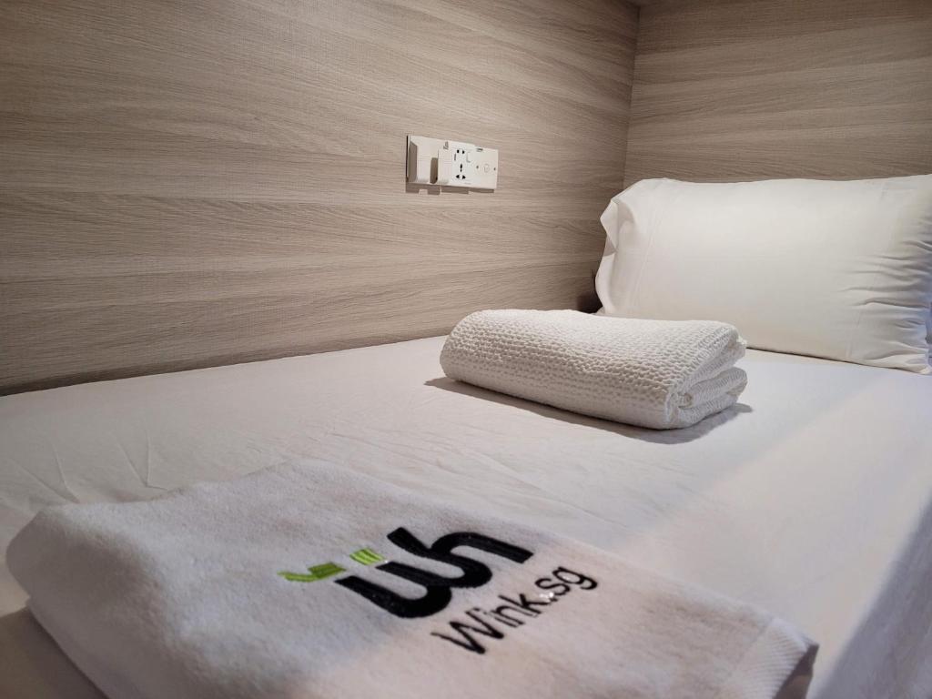 新加坡Wink at Upper Cross Street的一张带白色毯子和枕头的床