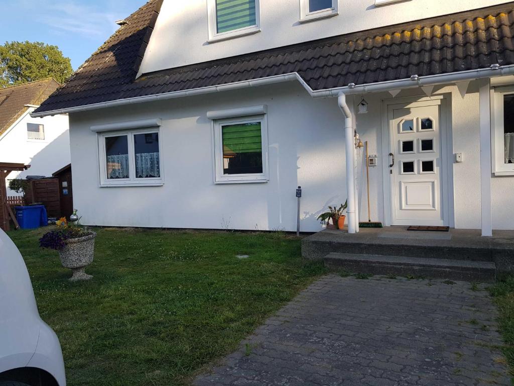 LütowFerienwohnung am Teich的白色的房子,有门和草地庭院