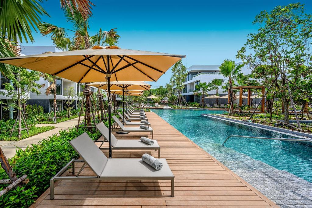 拉威海滩Stay Wellbeing & Lifestyle Resort的游泳池旁一排带遮阳伞的躺椅