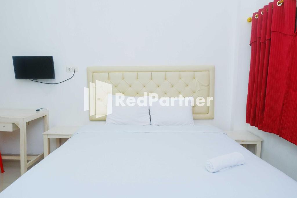 PampangFortuner Homestay Syariah Makassar Mitra RedDoorz的卧室配有白色的床和红色窗帘