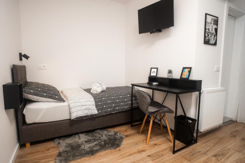 萨格勒布LaRoom - Free Parking的一间卧室配有一张带书桌和电视的床。