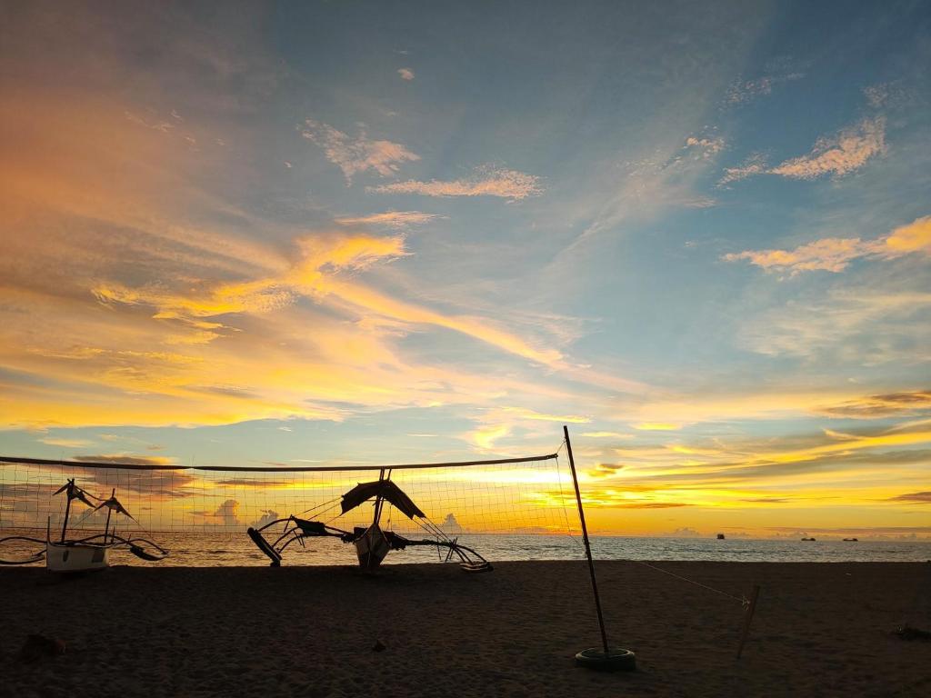 San NarcisoMope Beach Resort的海滩上的日落和遮阳伞