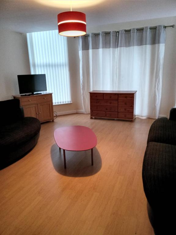 利物浦Sandringham House的客厅配有红色桌子和沙发