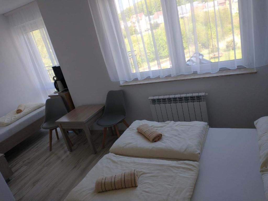 尼彻兹Bożenka的一间卧室设有两张床、一张桌子和窗户。