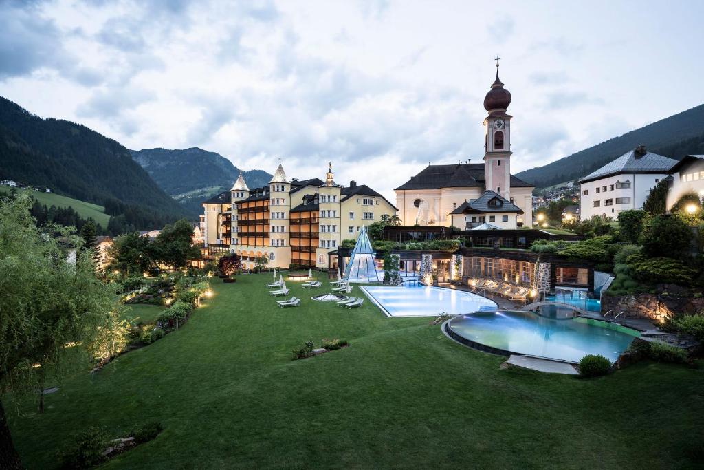 奥蒂塞伊Adler Spa Resort Dolomiti的一座带两个游泳池和大楼的度假村