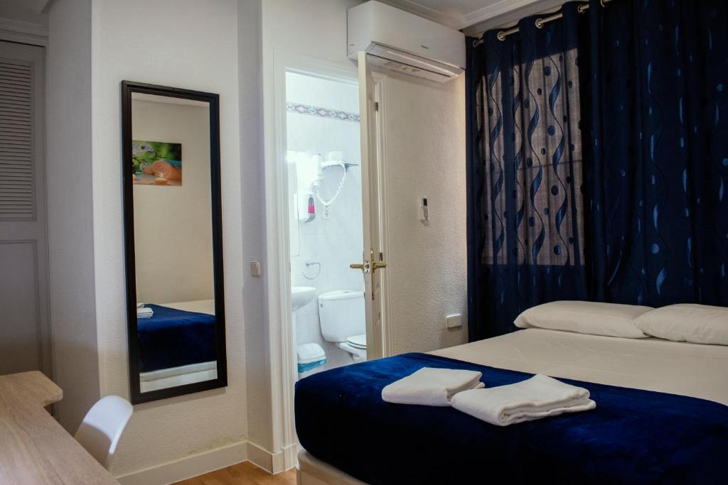 马德里Hostal Ártico的一间带一张床的卧室和一间带镜子的浴室