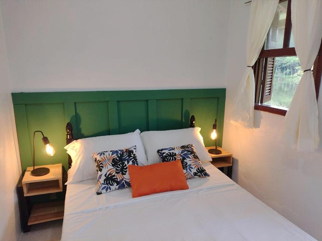 塔皮拉伊Lago 7 Cores的卧室配有白色床和橙色枕头
