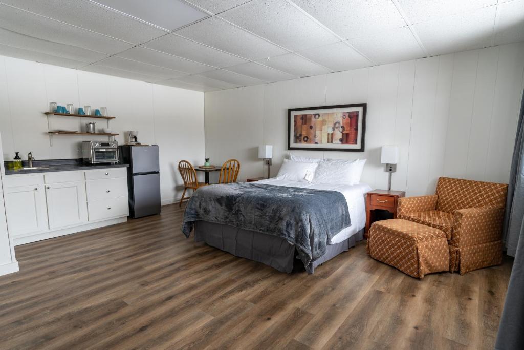 DeerwoodCuyuna Lakes Stay的一间卧室配有一张床和一把椅子,一间厨房