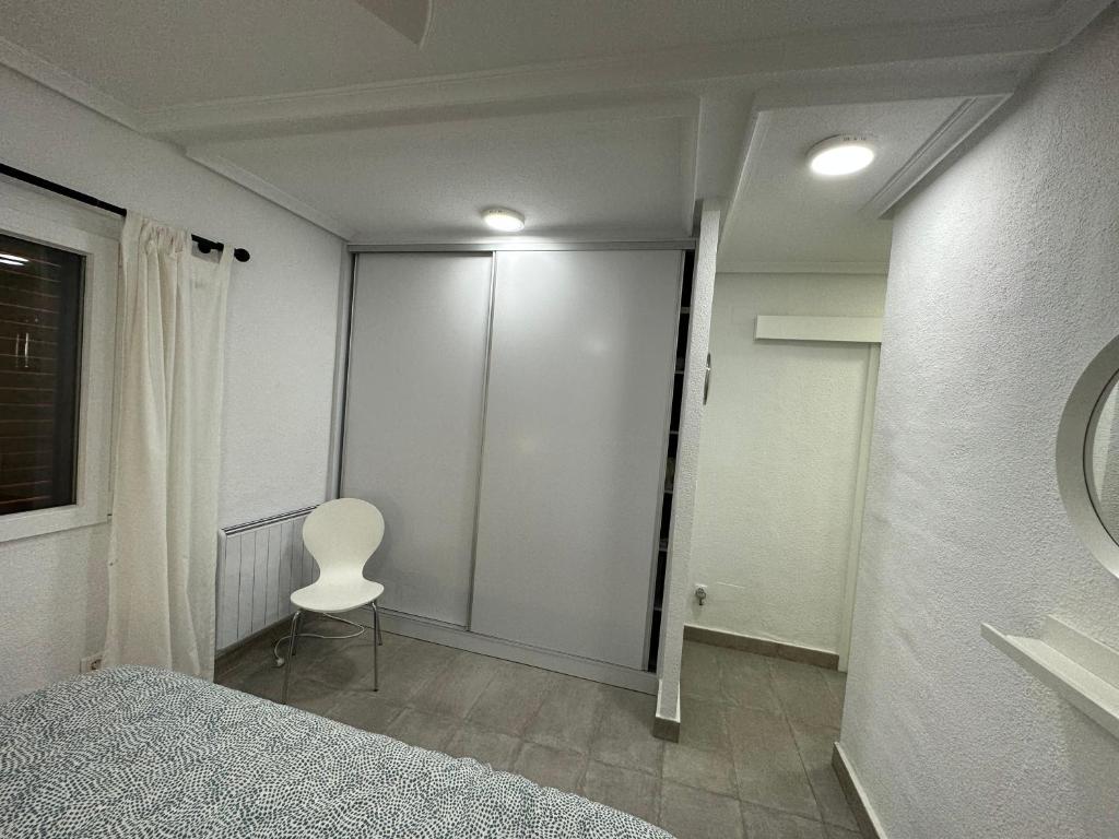 格兰阿利坎特Bungalow Santa Pola del Este的一间卧室配有一张床、一把椅子和镜子