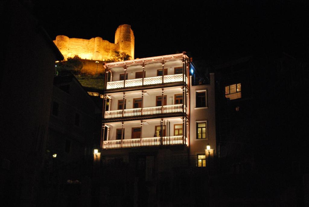 第比利斯格米街19号酒店的一座高大的白色建筑,晚上有灯