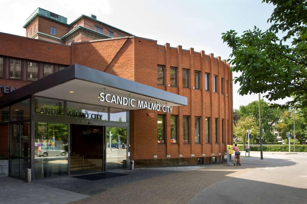 马尔默马尔默市斯堪迪克酒店的砖砌的建筑,前面有标志