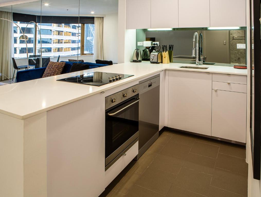 悉尼Quay West 1301 Self- Catering的厨房配有白色橱柜和炉灶烤箱。