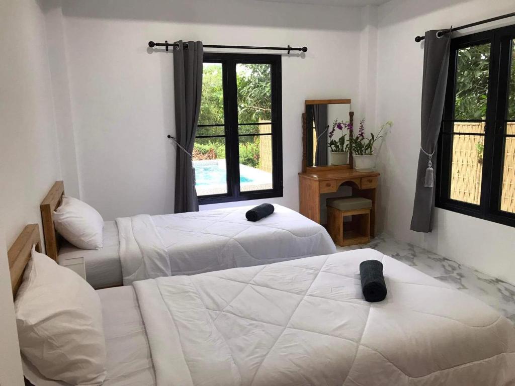 Ban Ai DaoVilla MILTONIA的一间卧室设有两张床和窗户。