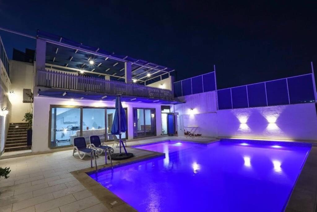 安曼Aqua Blue Villa-Dead Sea, Jordan的一座晚上设有游泳池的房子
