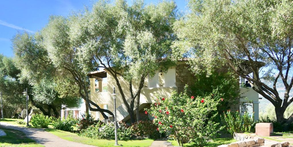 罗通多港Apartments in residence with swimming pool in Porto Rotondo的前面有树木和鲜花的房子