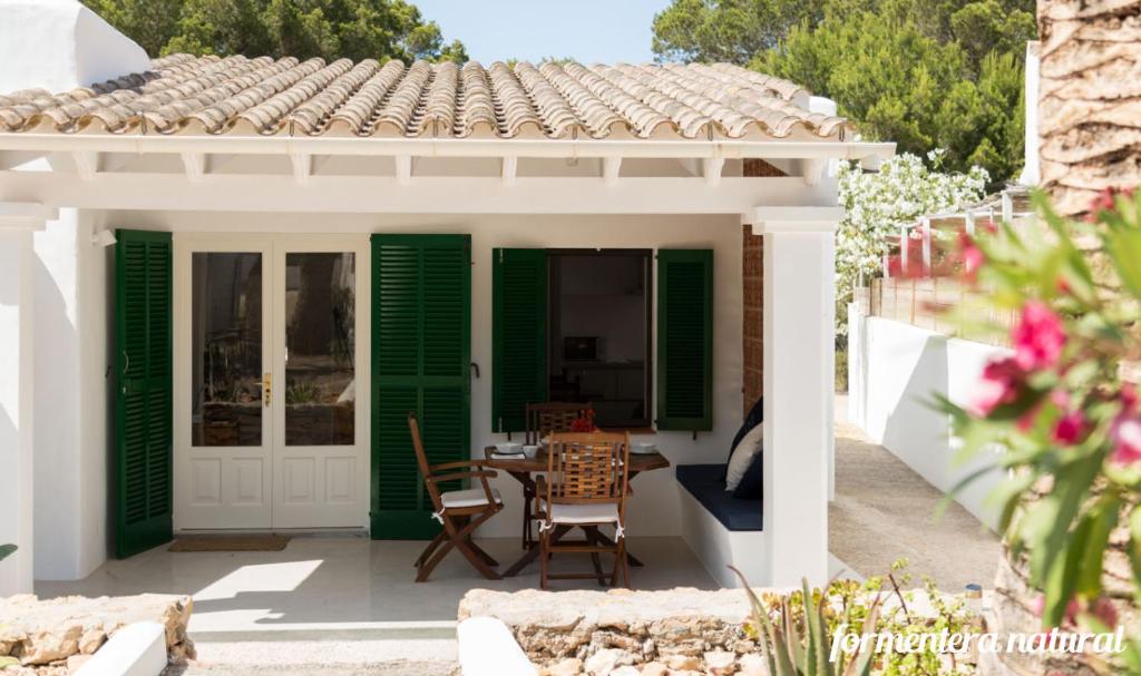 圣弗朗西斯科哈维尔Casas Emma y Sofía - Porto Sale - Formentera Natural的庭院设有绿色百叶窗和桌椅