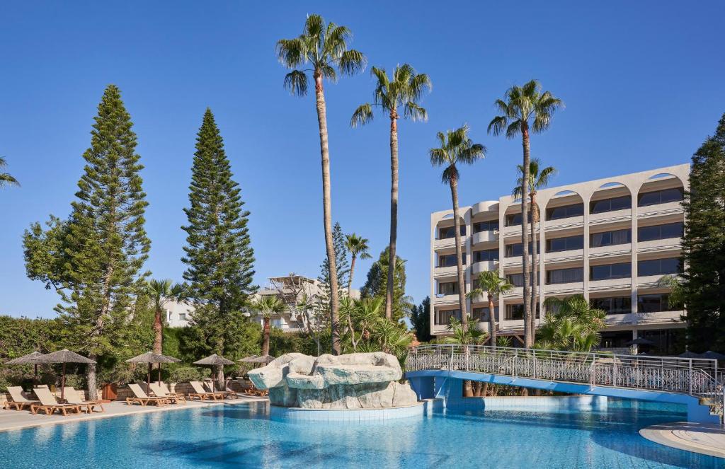 利马索尔Atlantica Oasis Hotel的一座棕榈树游泳池和一座建筑