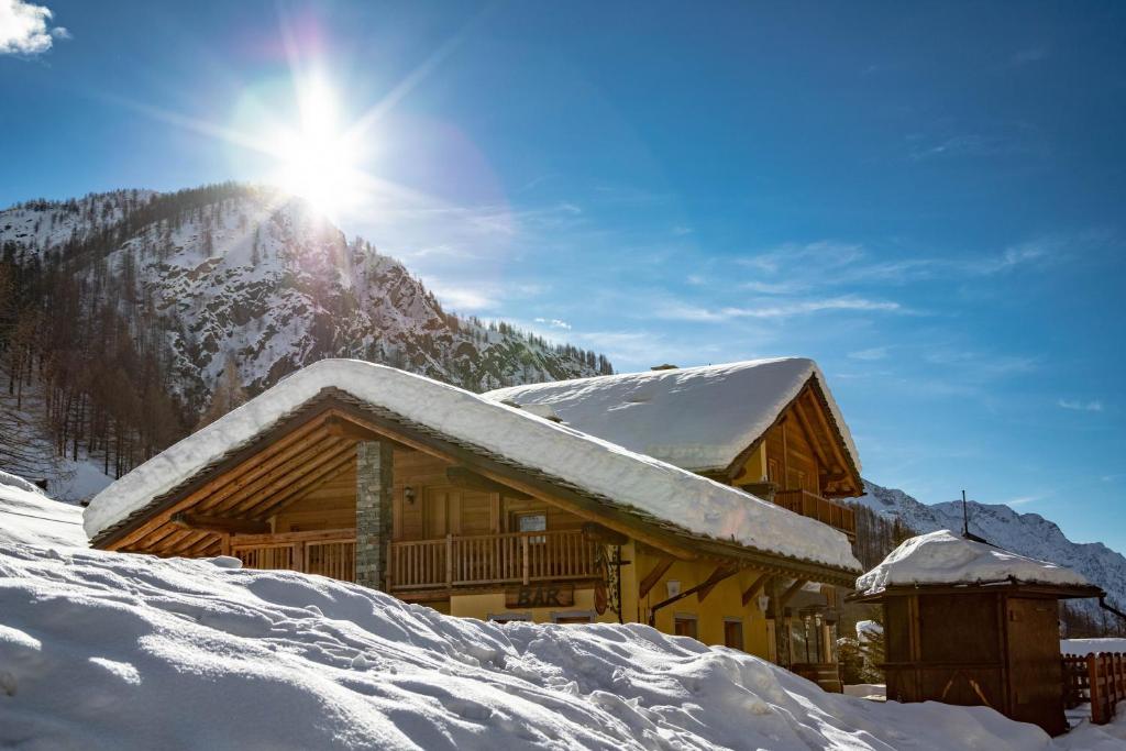 格雷索拉特里尼泰Walsertal Residence的雪覆盖的小木屋,后面有太阳