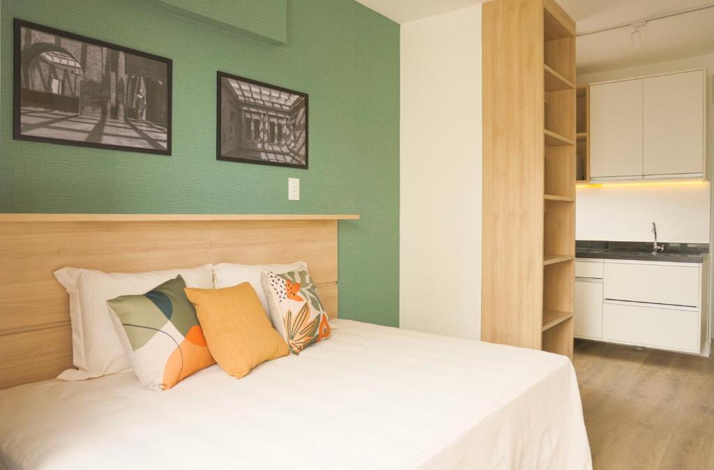 圣保罗XBase Studio Parque Augusta-Higienópolis Mackenzie的一间卧室设有绿色的墙壁和一张带枕头的床