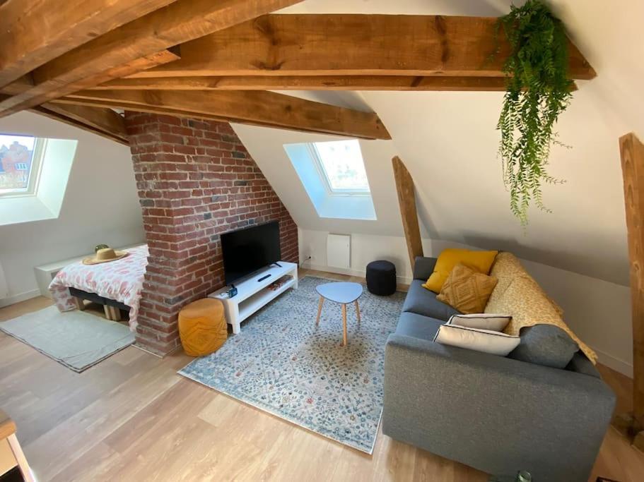 加来Chez Mathilde Studio Calais Nord Citadelle的带沙发和砖墙的客厅