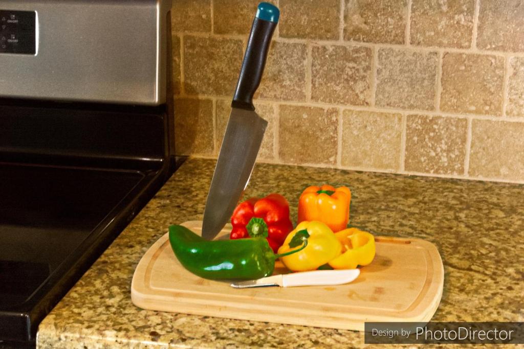 大学城Cool & Comfy Condo! Family Friendly!的刀子在切盘上,在柜台上放蔬菜