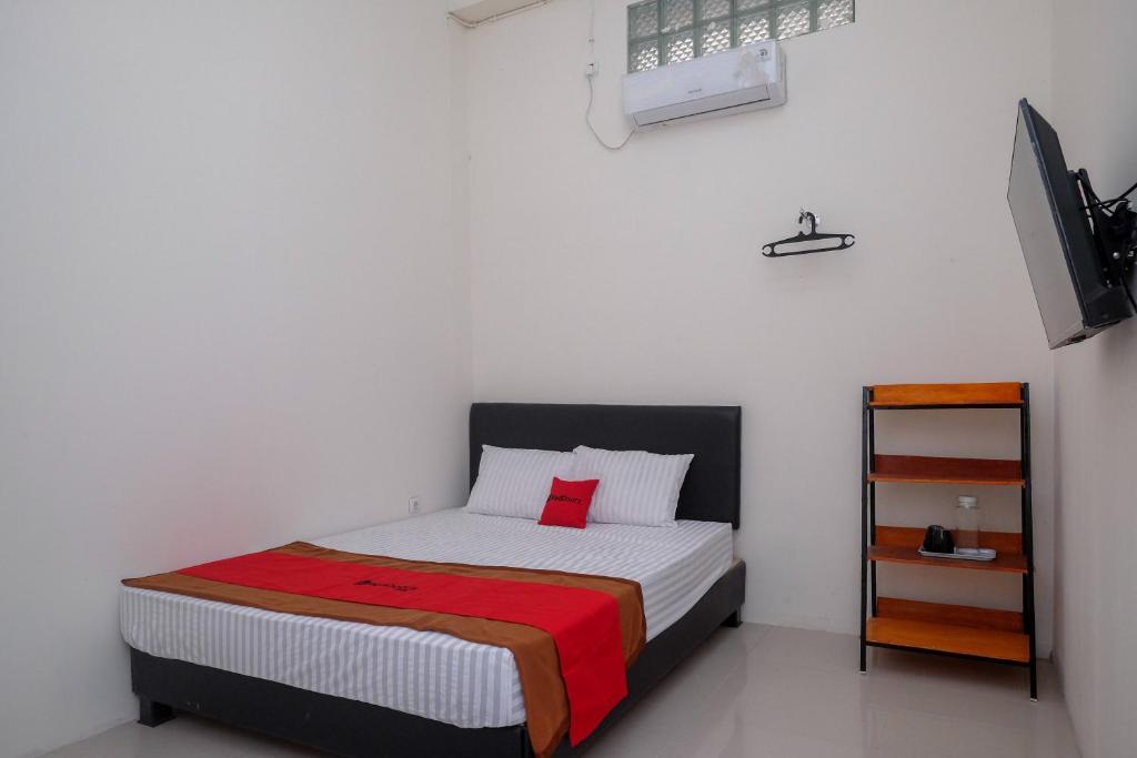 马格朗RedDoorz near Alun Alun Magelang 2的一间小卧室,配有一张带红色枕头的床