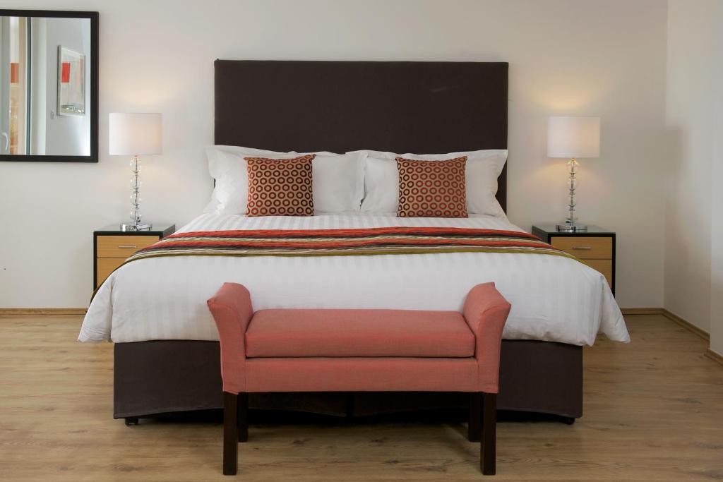 布达佩斯Escala Hotel & Suites的一间卧室配有一张大床和粉红色椅子