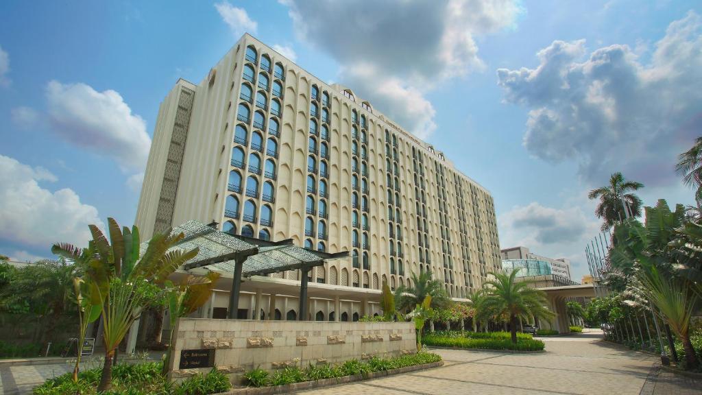 达卡InterContinental Dhaka, an IHG Hotel的一座棕榈树环绕的大建筑