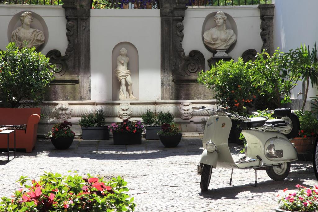 那不勒斯Hotel Piazza Bellini & Apartments的停在一座有雕像的建筑前的摩托车
