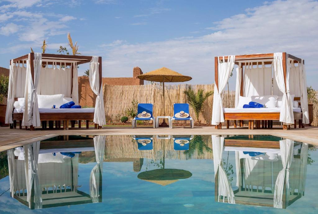 马拉喀什Maison Daouia的一个带游泳池、两张床和椅子的度假酒店