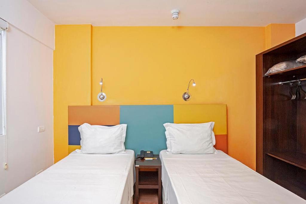 巴拉奈里奥-坎布里乌Tri Hotel Balneario Camboriu的黄色和蓝色的客房内的两张床