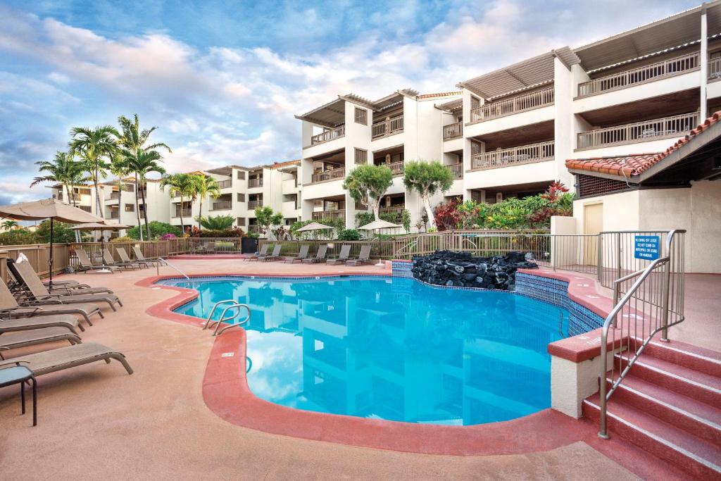科纳科纳海岸度假酒店的一座带椅子的游泳池以及一座建筑
