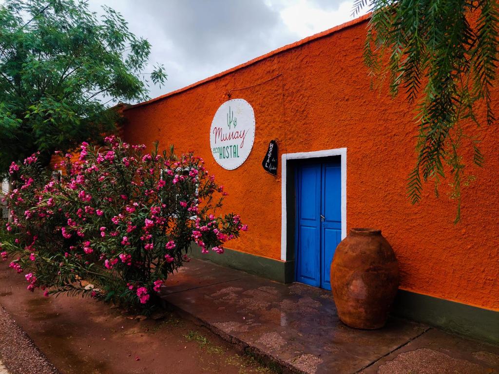 蒂诺加斯塔Munay EcoHostal - Cabañas de Adobe的橙色的建筑,有蓝色的门和鲜花