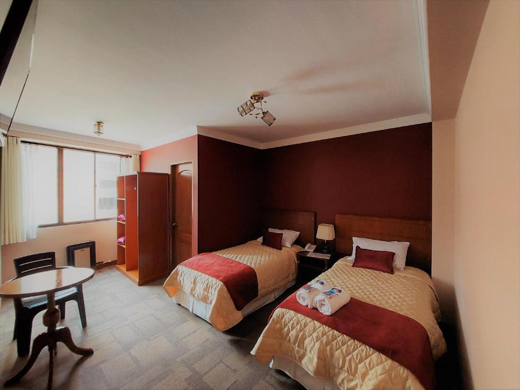 拉巴斯Hotel Boutique Vivenzo的酒店客房设有两张床和一张桌子。
