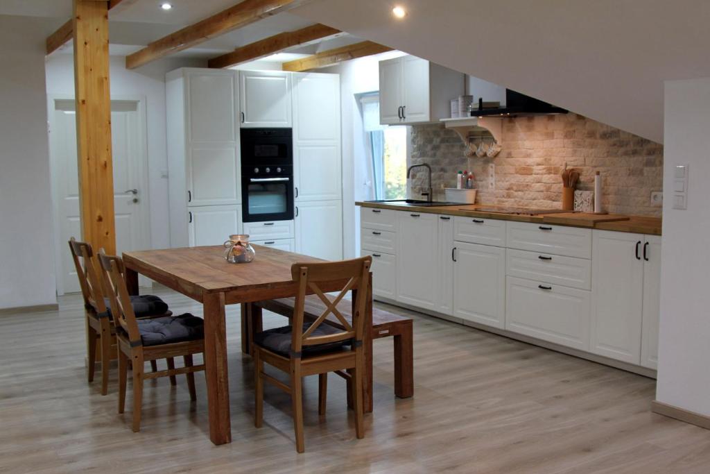 BernauFerienwohnung Stefanko的厨房配有白色橱柜和木桌及椅子