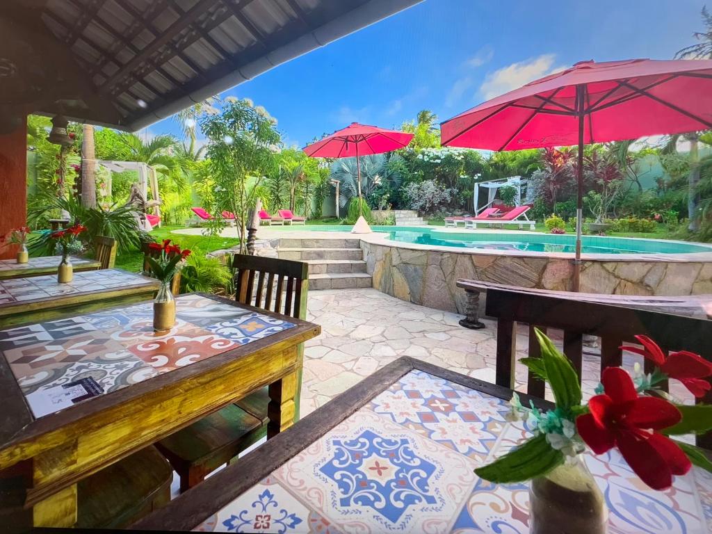 卡姆布库Xainã Pousada de Charme的一个带桌子和遮阳伞的庭院和一个游泳池