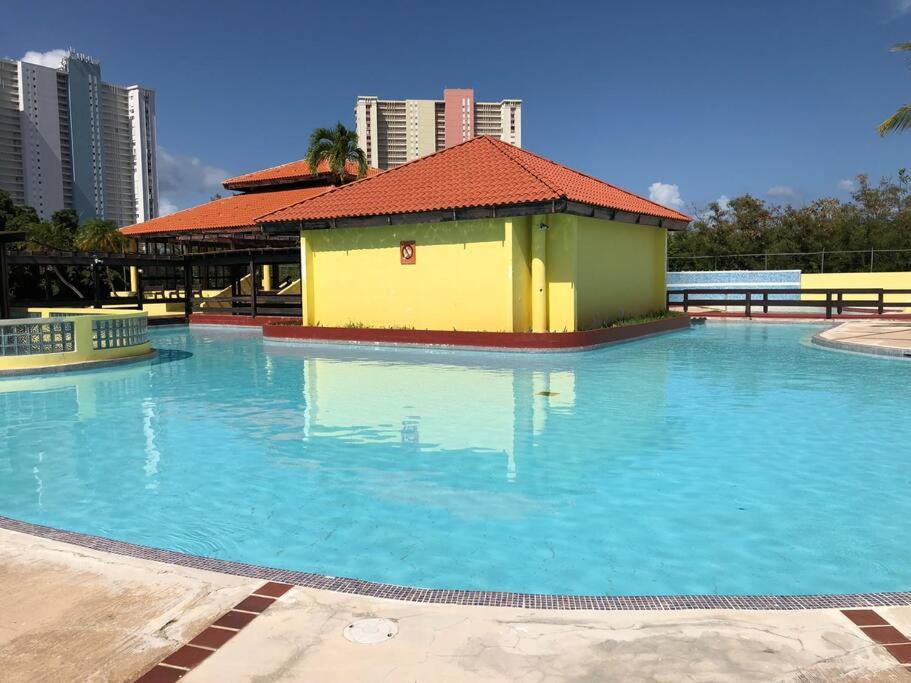 法哈多Casa Rosado @ Villa Marina Fajardo Pool Yunque的一座黄色和绿色建筑的大型游泳池