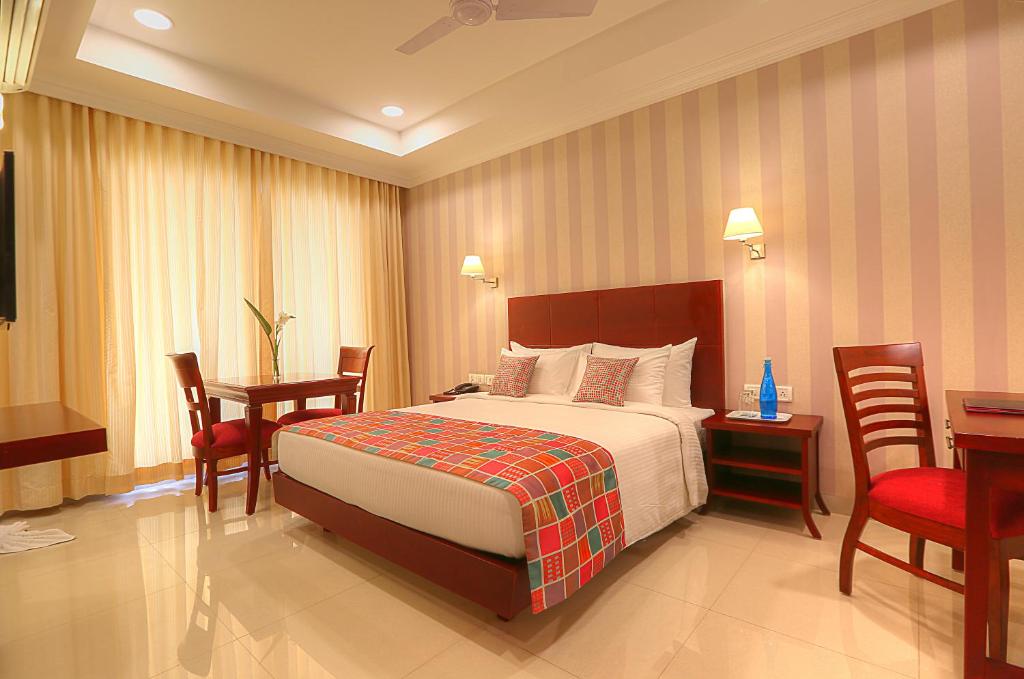 班加罗尔Lilac Hotel 3rd Block的酒店客房带一张床、一张桌子和椅子