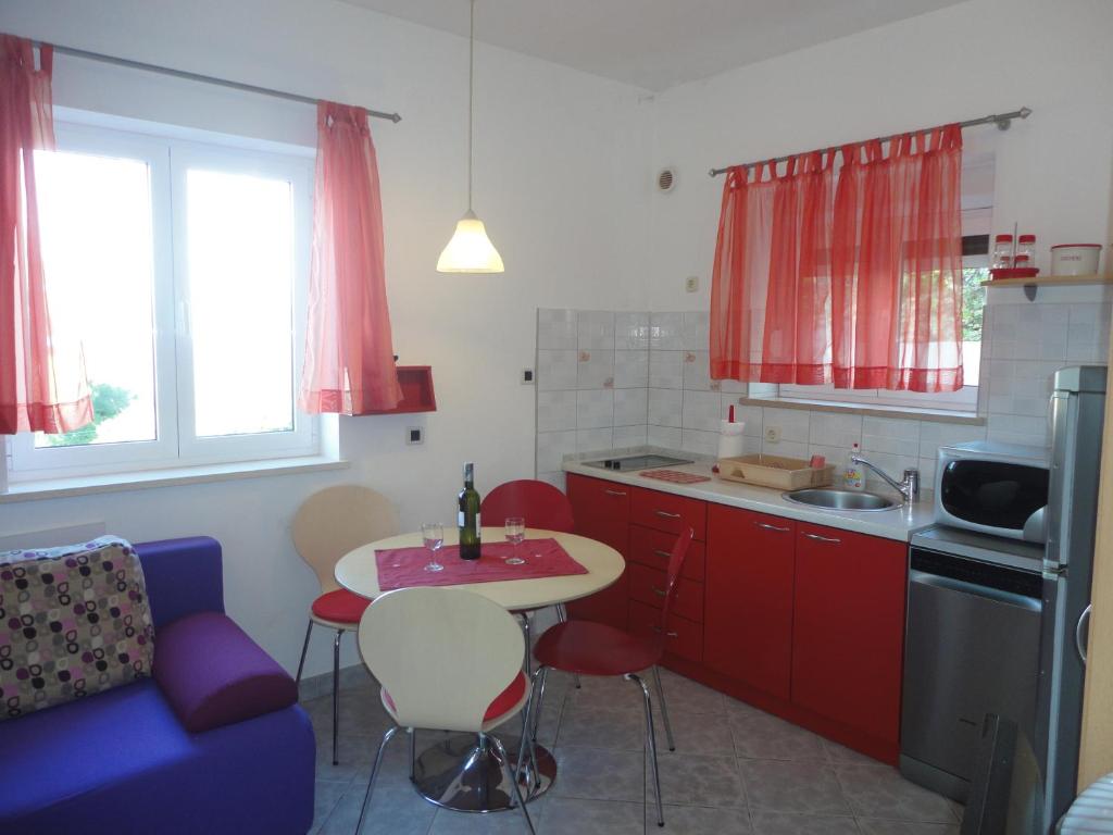 波斯蒂拉Lozna Apartment的厨房配有红色橱柜、桌子和蓝色沙发