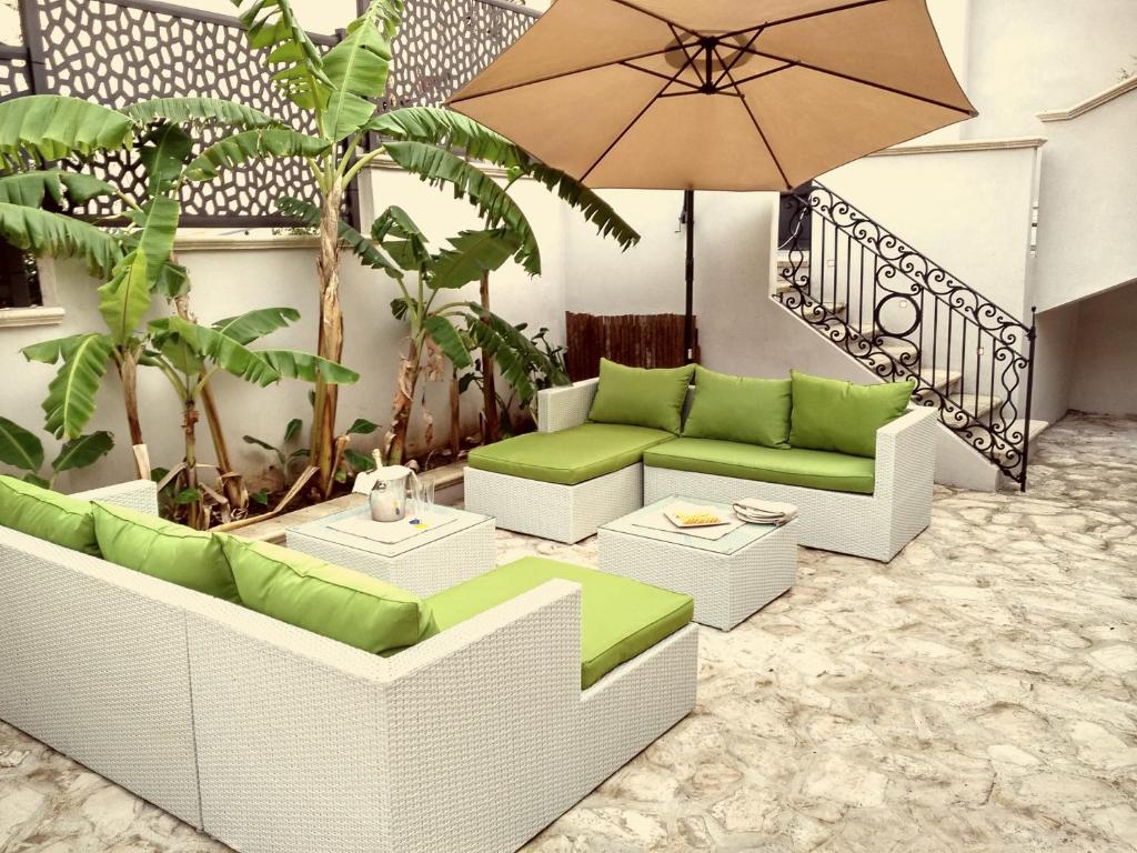 特罗佩阿米娜旅馆的庭院配有绿色和白色家具以及雨伞。