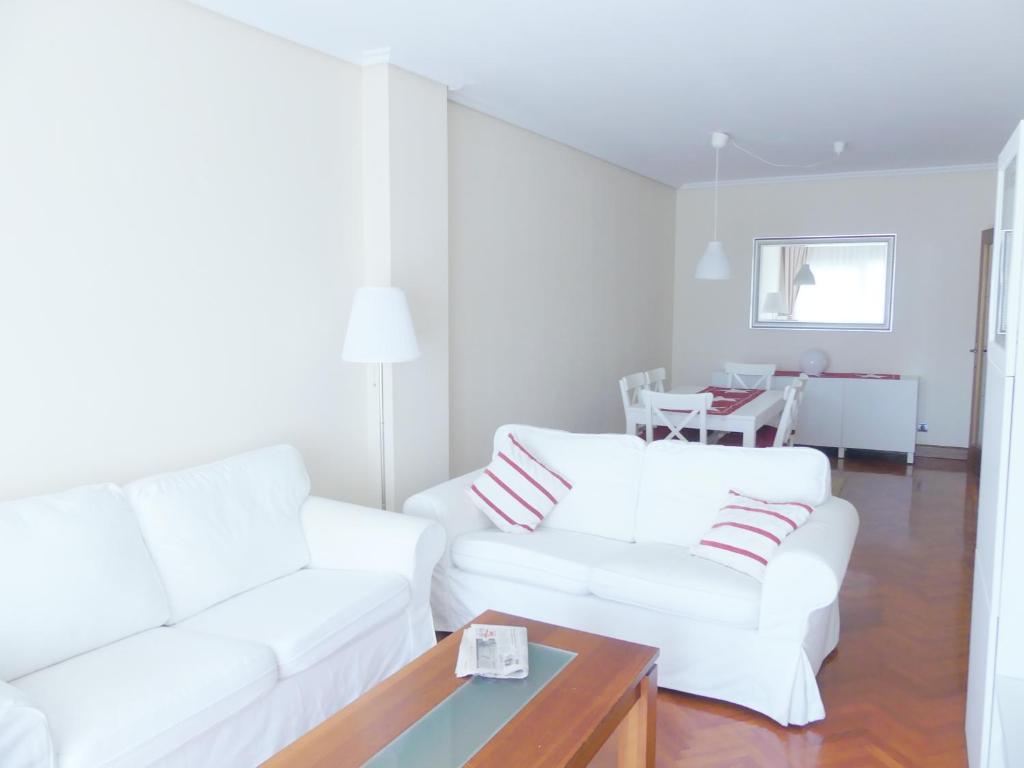 潘普洛纳Apartamento luminoso, funcional y amplio en zona hospitalaria的白色的客厅配有2张白色沙发和1张桌子