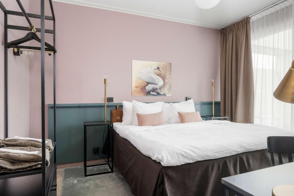 恩厄尔霍尔姆普鲁斯胡斯57贝斯特维斯特酒店的一间卧室配有白色床单和粉红色墙壁。