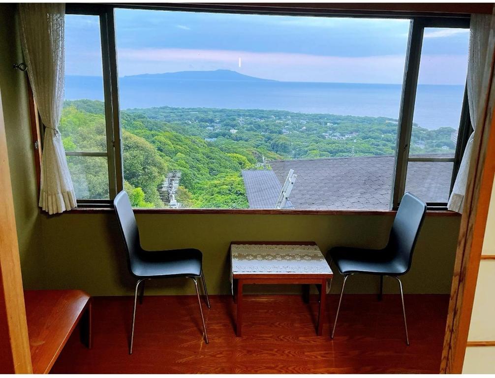 FutoIzu One Club - Vacation STAY 10342v的一张桌子和两把椅子,位于一个设有大窗户的房间