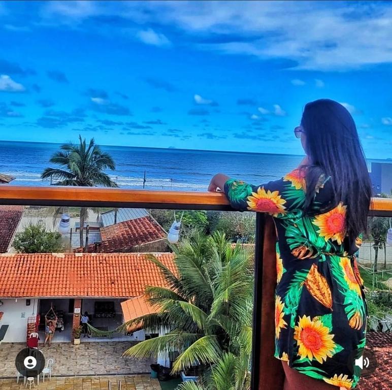 伊塔尼亚恩Hostel Praia Centro Itanhaém的站在一个眺望海洋的阳台上的女人