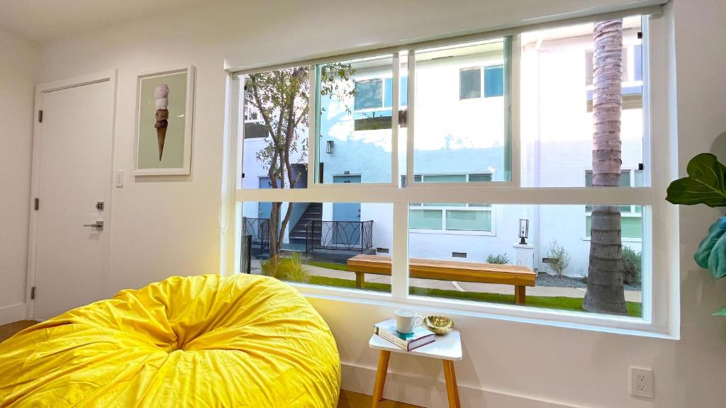 洛杉矶Kingsley Courtyard Apartment的客厅设有大窗户和黄色的搁脚凳