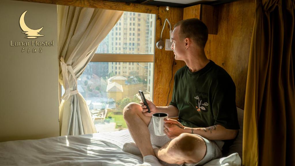 迪拜Lunar Hostel Plus的坐在床上看手机的人