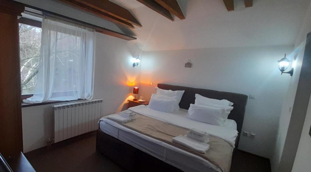 萨拉热窝Teuta Palace Dom Faletići的卧室配有带白色枕头的床和窗户。
