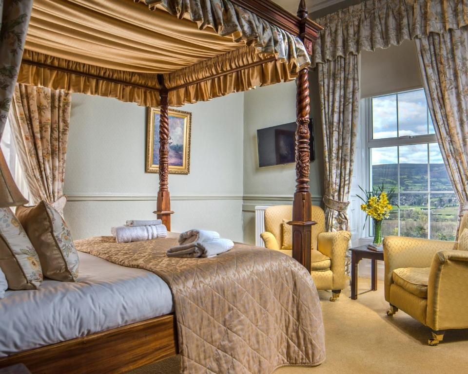 克里克豪厄尔曼诺酒店的一间卧室配有一张天蓬床和两把椅子