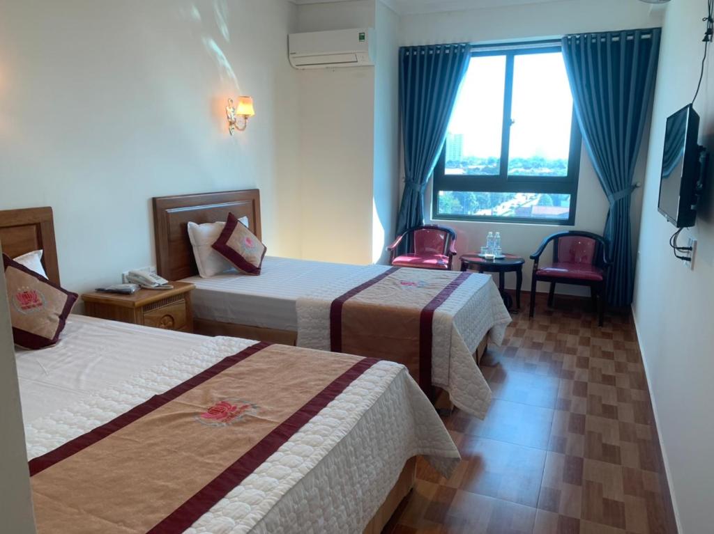 荣市Trường Thịnh Hotel的酒店客房设有两张床和窗户。