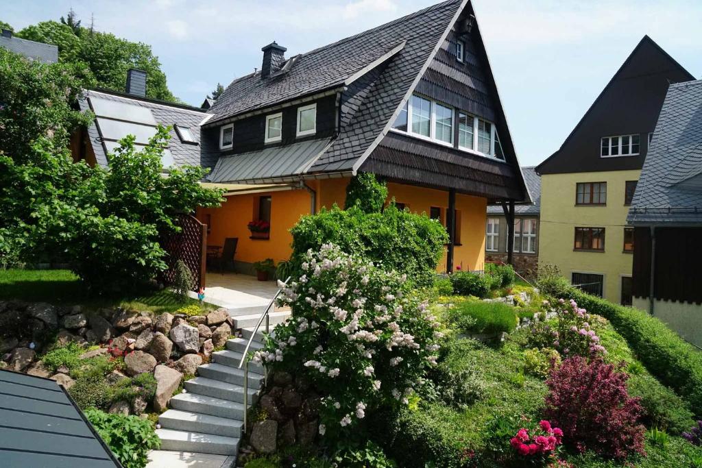 库罗阿尔滕堡Ferienwohnung Splitek的黄色的房子,有黑色的屋顶和一些花
